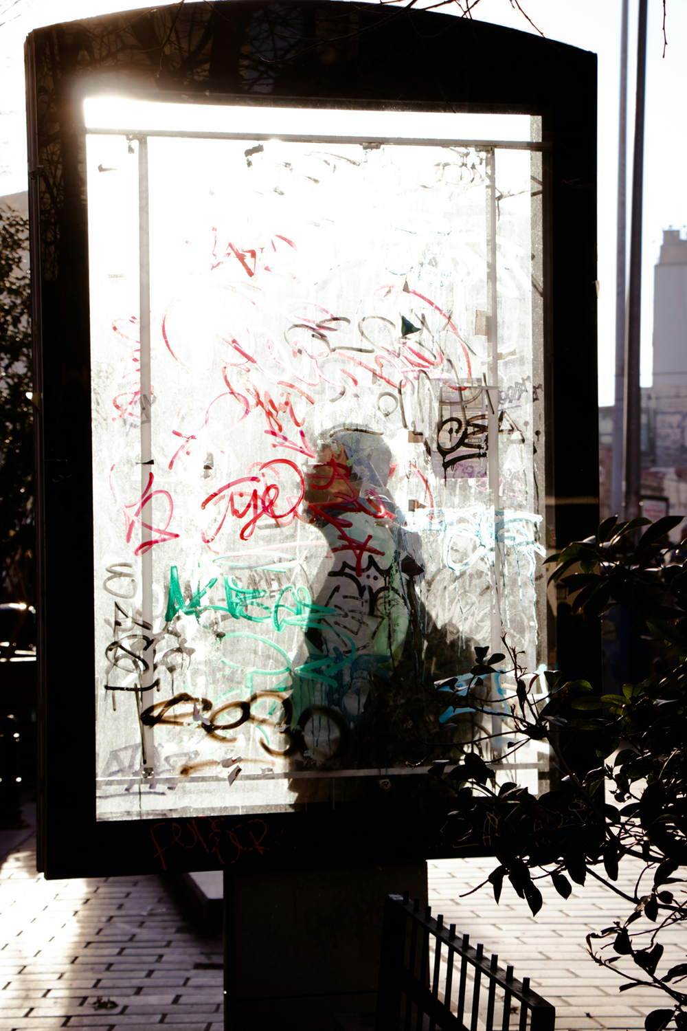 Heavily vandalized glass surface showing graffiti damage that GlassLock anti-graffiti film prevents